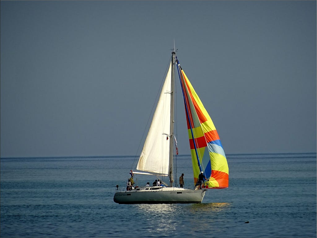 Gray and White Sail Boat With 5 Person Riding on the Middle of the Body of Water